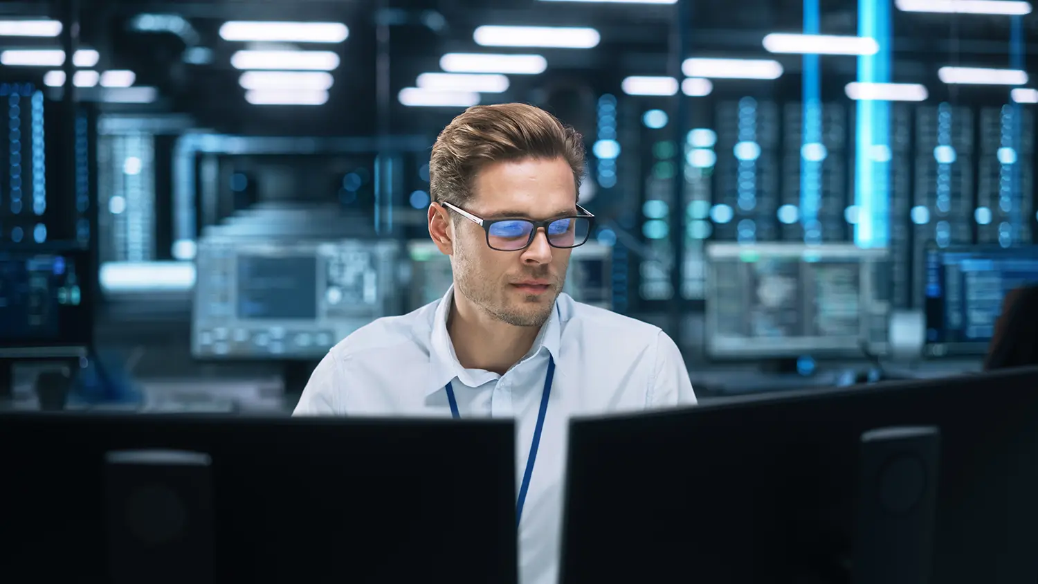 Ein Systemadministrator sitz fokussiert vor seinen Bildschirmen und hat dank Monitoring und Netzwerktransparenz alles im Griff