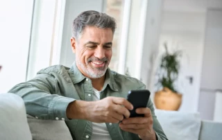 Mit Transaktionsmails den E-Commerce-Erfolg steigern. Ein Kunde kauft zufrieden auf dem Handy im Internet ein.